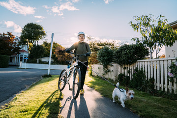 19/4/2020 Asian woman with a bike walking with a dog in autumn at the Botanic garden, Oamaru, New Zealand. Concept about exercise while social isolation from Coronavirus or Covid 19.