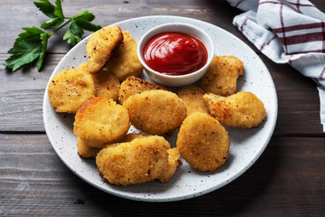Fried chicken nuggets with tomato ketchup sauce. Wooden background. Copy space.