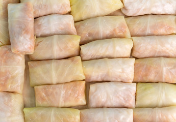 Detail of a tray full of fresh rolled stuffed cabbage, which are preparing to bake.