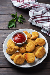 Fried chicken nuggets with tomato ketchup sauce. Wooden background. Copy space.