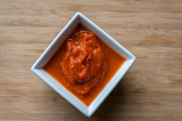 Rote Sauce in Schale auf Holzhintergrund