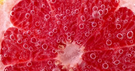 Half of a ripe grapefruit under water with air bubbles.