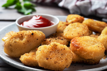 Fried chicken nuggets with tomato ketchup sauce. Wooden background. Copy space.