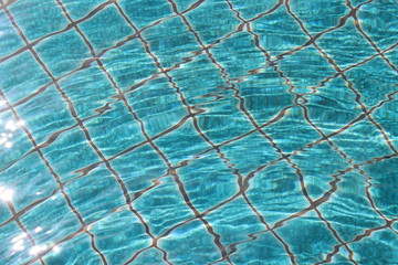 Blue swimming pool tiles with ripples and reflections