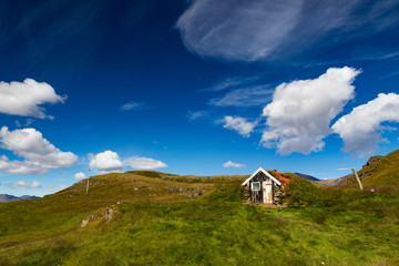 Fototapeta na wymiar Small shed on a grassy hill under deep blue sky