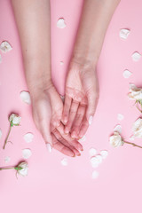 Obraz na płótnie Canvas Elegant and graceful womans hands on pink background with flowers