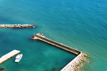 A lone white boat moored at the sea on a Sunny day. Pier with access to the blue sea.