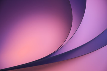 Curved sheets of paper with colourful backlight forming abstract background