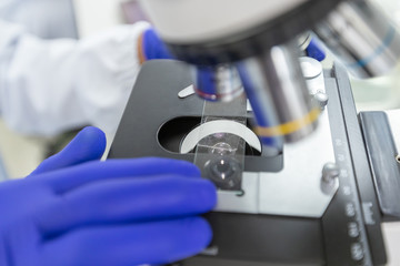 Scientist using microscope with slide sample coronavirus or covid-19, Concept science and Technology