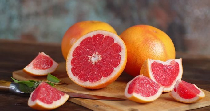 Cut fresh grapefruit with a knife on a cutting Board rotates slowly.