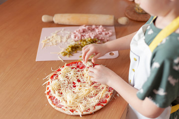 child cook preparing pizza in his kitchen