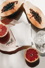 Papaya and grapefruit on pink plate, glass of water and rosemary herb. Blank greeting card mockup...