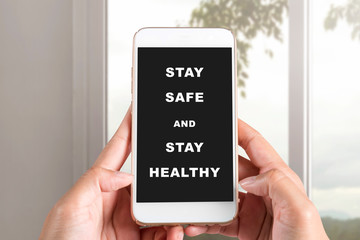 Hands holding a mobile phone with a message for Stay safe and stay healthy on the screen