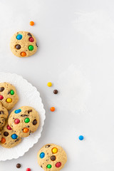 Fresh homemade cookies with color chocolate coated candies on white background. Holiday background. Top view, copy space