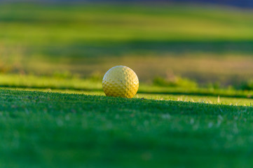 Excellent well-kept green grass lawn on large golf course, green section with big yellow foam ball for beginners on Tenerife island, Canary, Spain