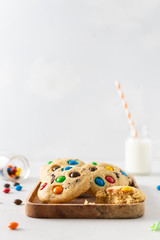 Cookies with colorful candies and chocolate chips on white background. Side view, copy space. Multicolor biscuits for holidays. Pastry, party background