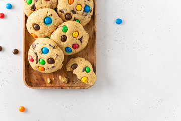 Homemade vanilla cookies decorated with multi-colored candy drops on wooden tray on white background. Top view, copy space