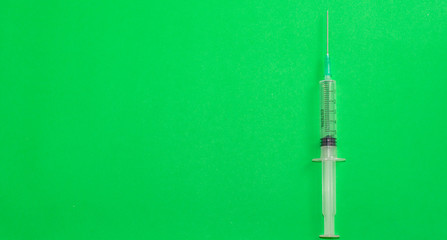empty syringe with needle on green background