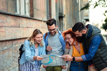 Group of smiling tourists enjoying on vacation, young friends having fun walking on city street during the day.