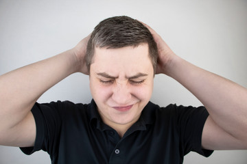 A man holds his head with his hands. Sensation of headache, migraine and dizziness. Headaches from stress or overwork