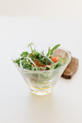 vegetable salad in a glass salad bowl with brown bread with seeds on a white background