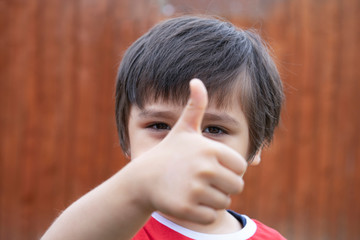 Cropped of school kid giving thumb up as sign of success, Selective focus Child  showing his finger, Litle boy relaxing ootside in sunny day spring or summer, Positive children concept