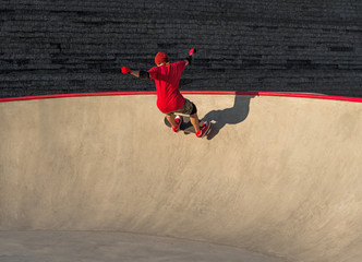 Young active man riding skateboard in skatepark pool
