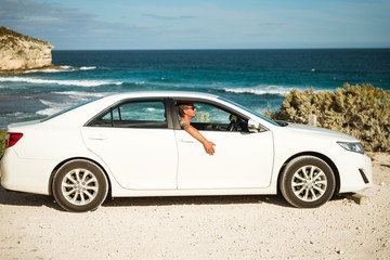 Fototapeta na wymiar Young handsome man in a white car parked on the Australian ocean coast 