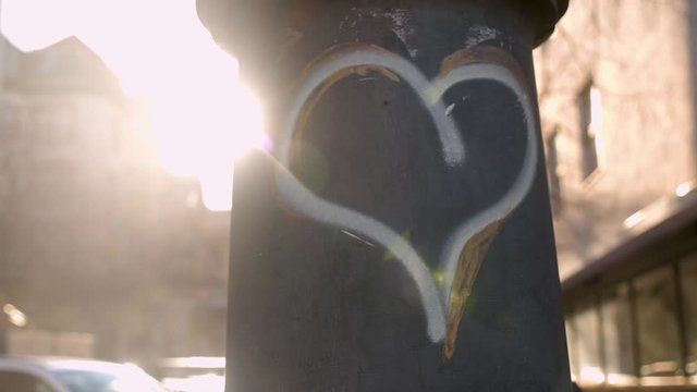 painted heart on a bollard in a city pulsing in backlight