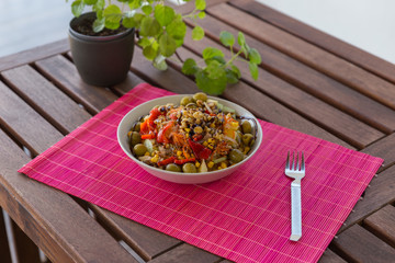 Tasty Mediterranean salad on fuchsia tablecloth and wooden table