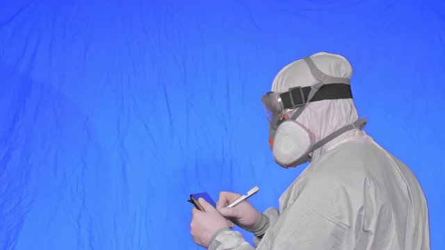 Scientist virologist in respirator makes write in an tablet computer with stylus. Man wearing protective medical mask. Concept health safety virus coronavirus epidemic 2019 nCoV. Chroma key blue.