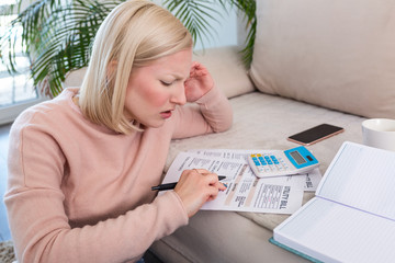 Beautiful young Albino woman sitting with calculator and bills, doing paperwork. Hand woman doing finances and calculate on desk about cost at home office.Concept work from home