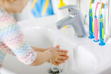 Closeup of little toddler girl washing hands with soap and water in bathroom. Close up child...