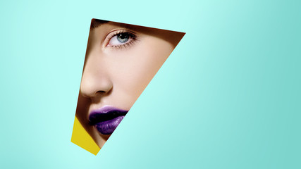 Plump bright purple lips in turquoise paper frame. Young model face. Close up beauty portrait....