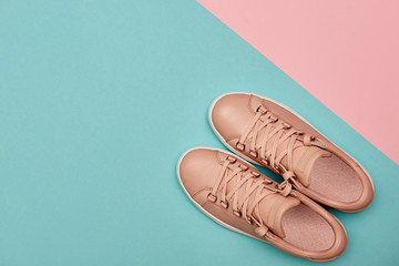 Stylish pink female shoes on pastel background, copy space. New sneakers on pink and blue background. Beauty and fashion concept. Flat lay, top view. Overhead shot