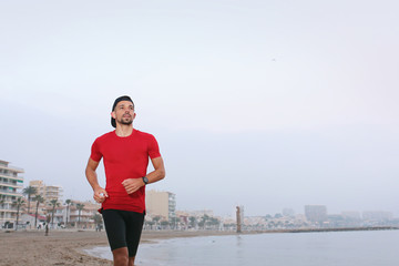 Running by the sea, training on the beach. A young athletic attractive man runs alone by the sea.