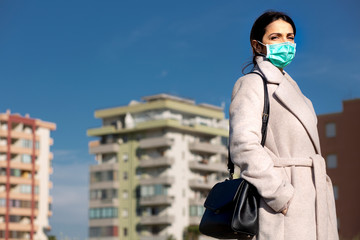 ragazza mora con cappotto indossa seria una mascherina protettiva chirurgica e sullo sfondo dei...