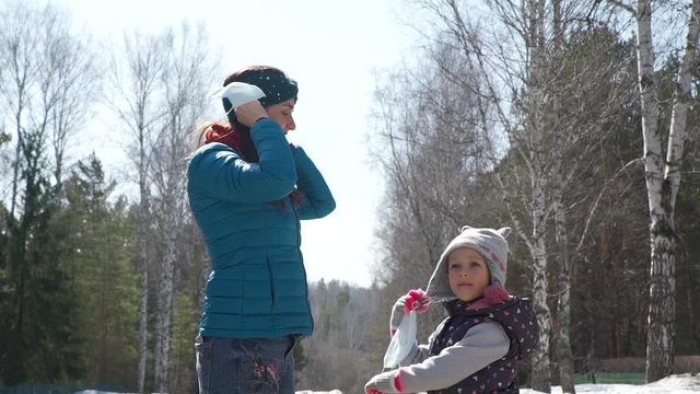 Little Girl with Mom Taking Off Protective Medical Masks in a Spring Park. Walking on the Opne Air. Health, Safety, Pandemic Concept