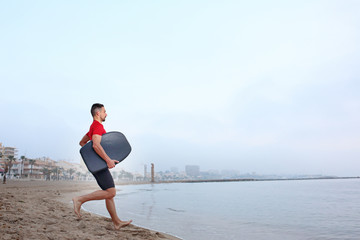 Skimboard, man swims on the board. A man in thermal foam does water sports in the sea.