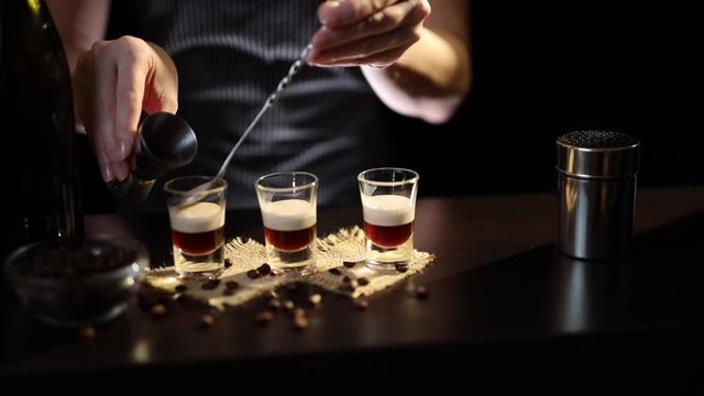 Barmaid making B-52 layered cocktail