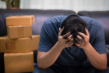 The young man is having a headache sitting on the sofa, the business concept failed to deliver