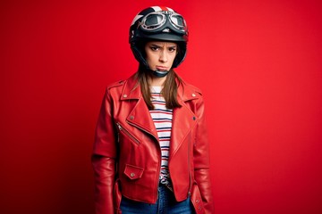 Young beautiful brunette motocyclist woman wearing motorcycle helmet and red jacket skeptic and nervous, frowning upset because of problem. Negative person.