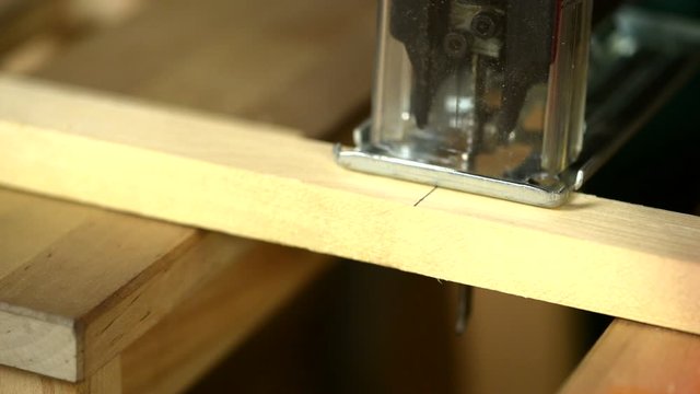 Close-up. A carpenter uses an electric saw to cut wooden planks.
