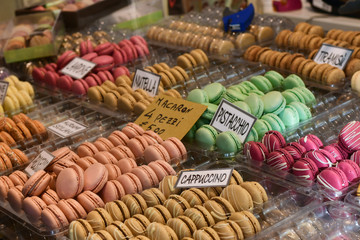 multicolored dessert macarons ( macaroon)  at the local sweet market. white signs in Italian and English indicate the taste of macarons