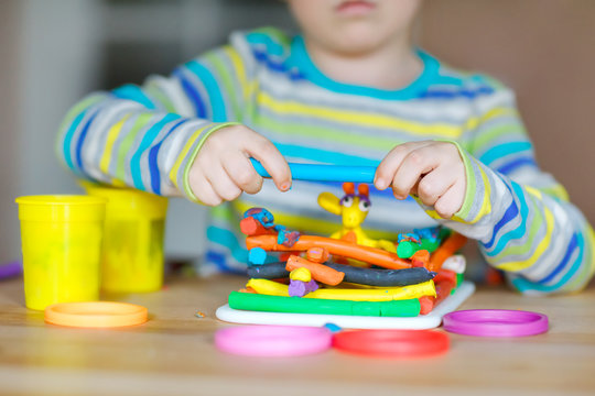 Close-up of hands of little boy having fun with dough, colorful modeling clay. Creative leisure with children. during corona virus quarantine staying at home. Shelter in place, lockdown concept.