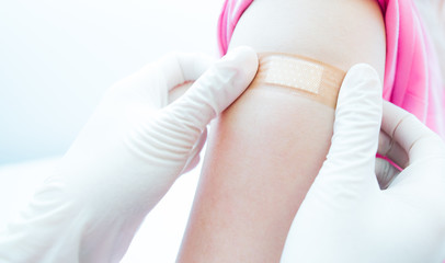 Closed would with Adhesive bandage plaster on a female brachium after vaccination, Adhesive bandage on arm after injection vaccine or medicine,ADHESIVE BANDAGES PLASTER - Medical Equipment,