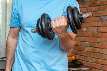 Fototapeta na wymiar dumbbell in the man hand doing fitness sport exercise at home close up