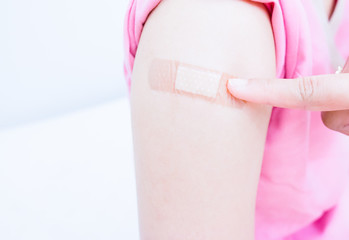 Closed would with Adhesive bandage plaster on a female brachium after vaccination, Adhesive bandage on arm after injection vaccine or medicine,ADHESIVE BANDAGES PLASTER - Medical Equipment,