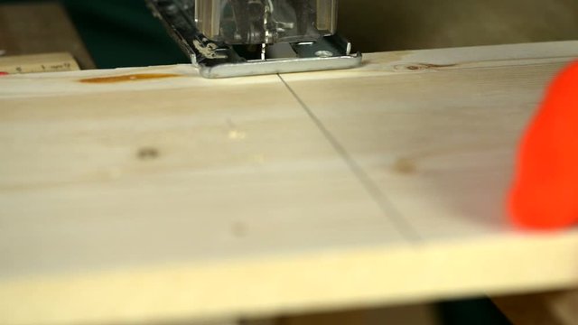 Close-up. A man uses an electric saw to cut wooden planks.