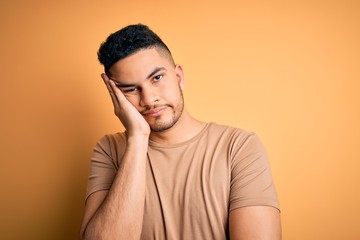 Young handsome man wearing casual t-shirt standing over isolated yellow background thinking looking tired and bored with depression problems with crossed arms.
